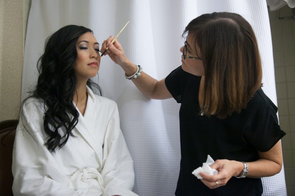 Makeup artist applies final makeup to bride